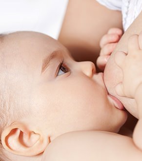 Close-up photograph of a baby drinking from the breast